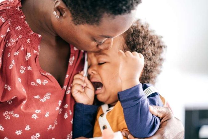 Une mère réconforte son jeune enfant en pleurs qui fait une crise de colère à la maison.