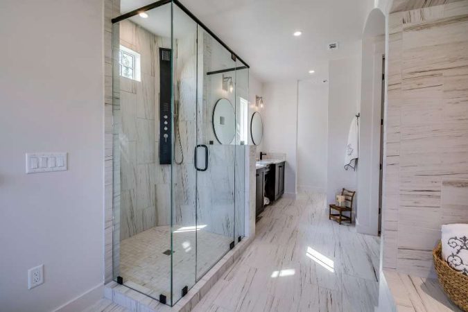 Une cabine de douche moderne en verre et marbre blanc, idéale pour illustrer les problèmes de mauvaise évacuation dans la douche.