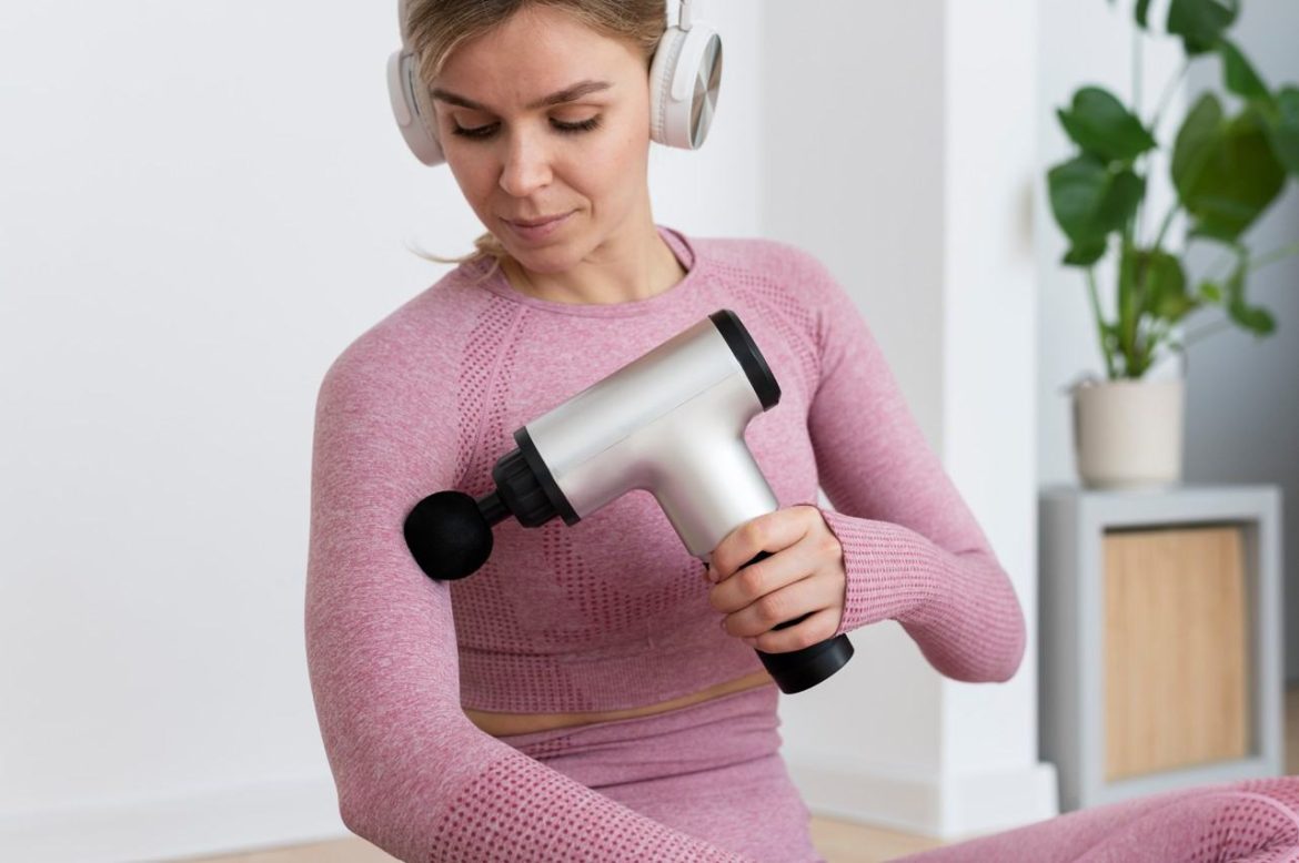 Femme sportive appliquant un pistolet de massage sur son bras pour savoir comment utiliser un pistolet de massage contre les courbatures