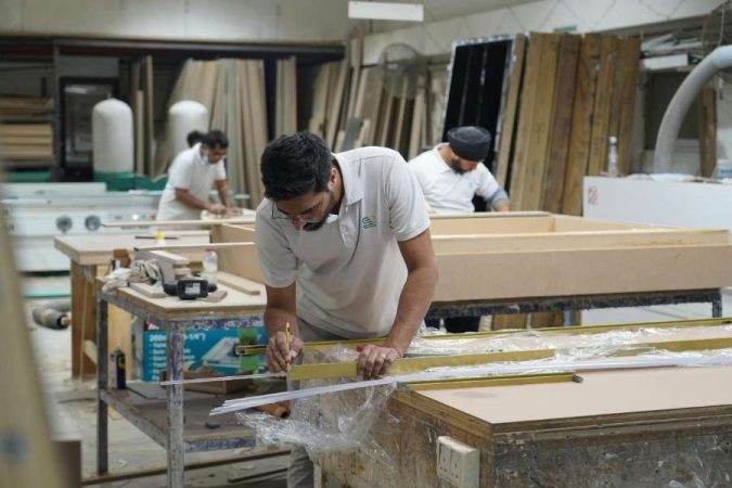 Un menuisier concentré travaille sur un établi en bois robuste dans un atelier de fabrication.