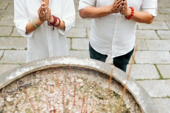 Des personnes prient ensemble près d'un grand réceptacle, symbolisant les traditions qui entourent la remise d'une médaille de baptême pour adulte.